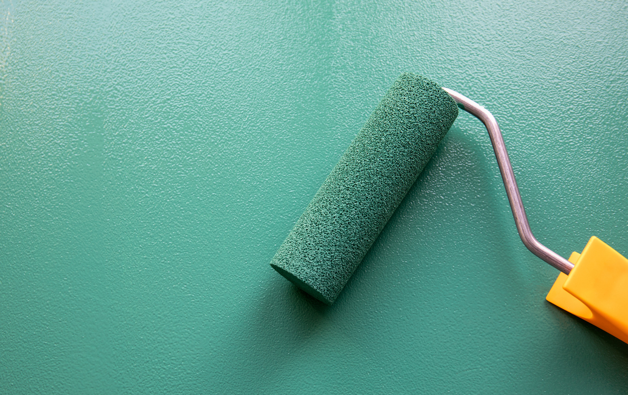 Applying exterior paint with a roller on a Livermore home