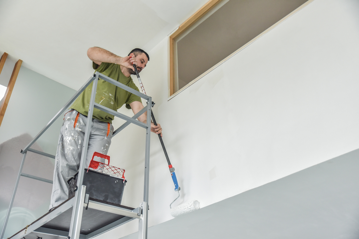 Profesional painter painting with paint roller.