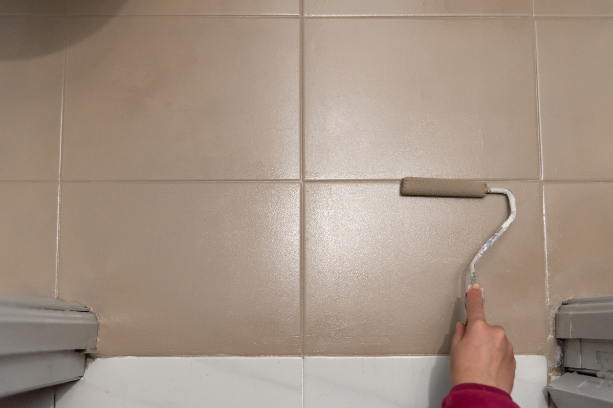 Painting tile bathroom floor with roller.