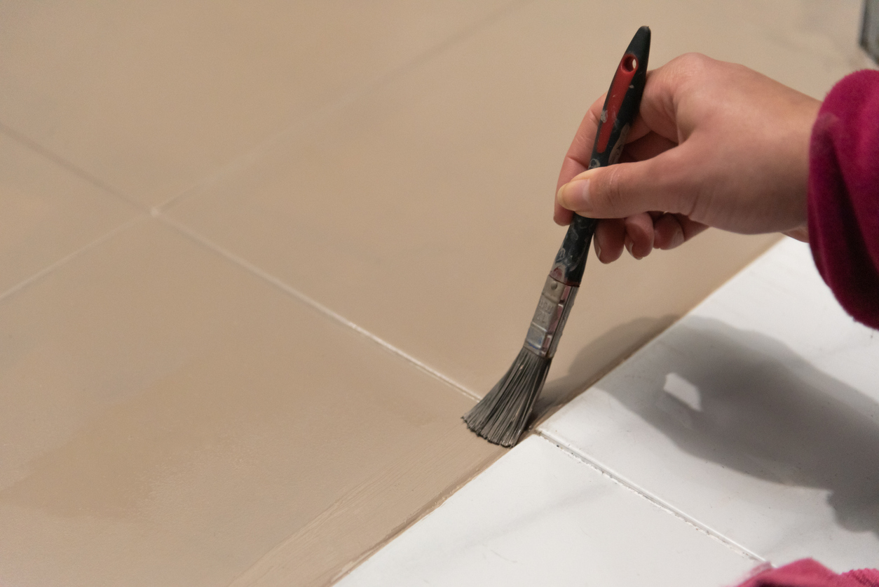 Painting tile with a paint brush in a bathroom.