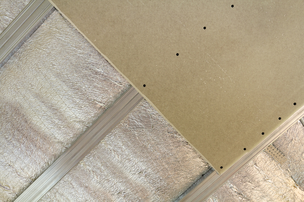 Room under construction with silver aluminum insulation foil and drywall on walls and ceiling.