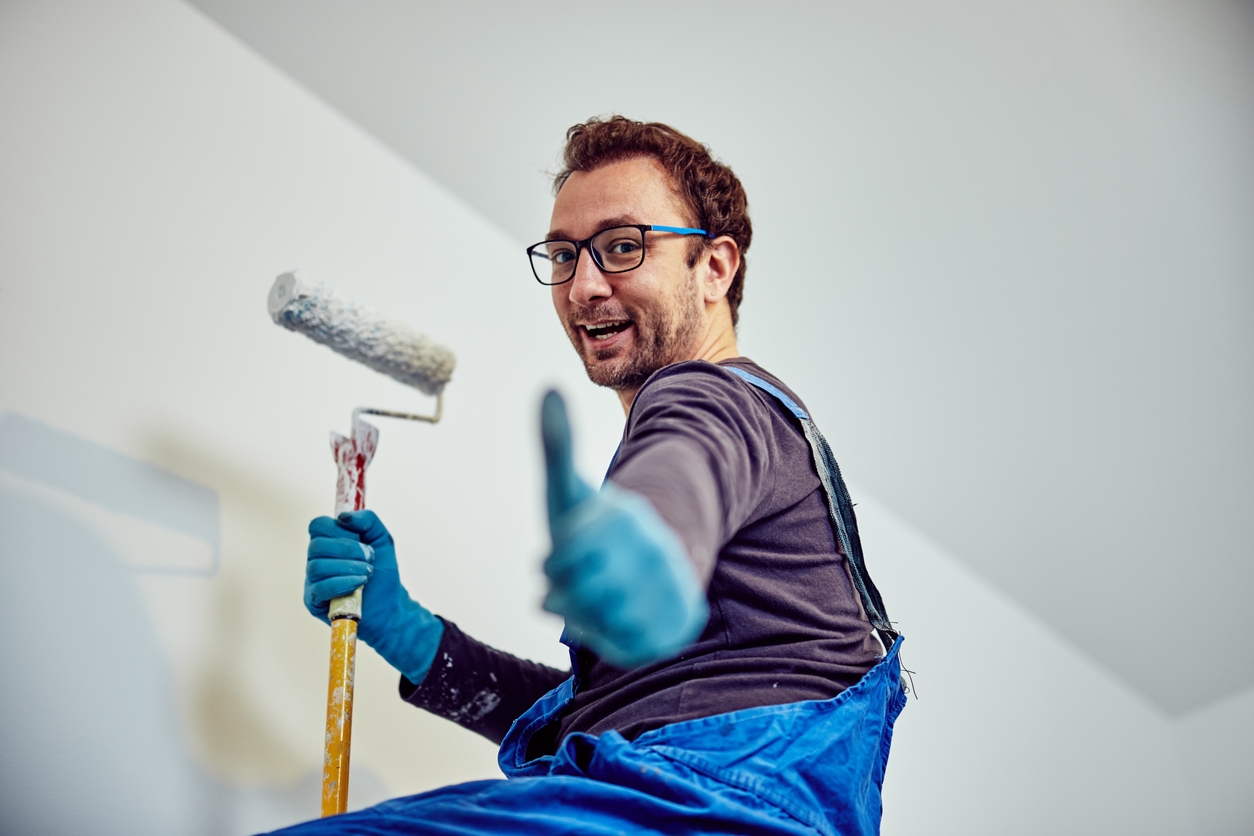 Worker painting walls inside the house - renovation fixes.