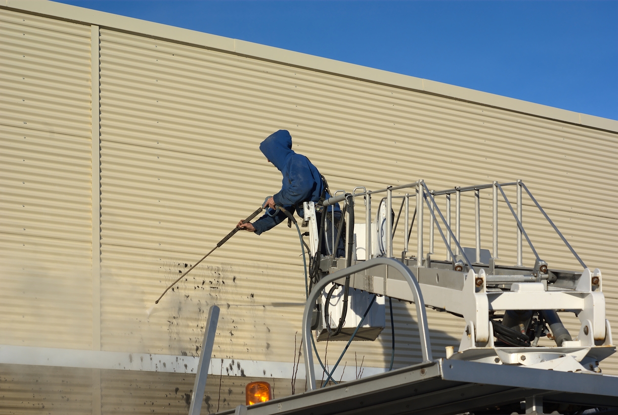 Custom Painting Inc. professional utilizing a pressure water jet to clean an external wall 