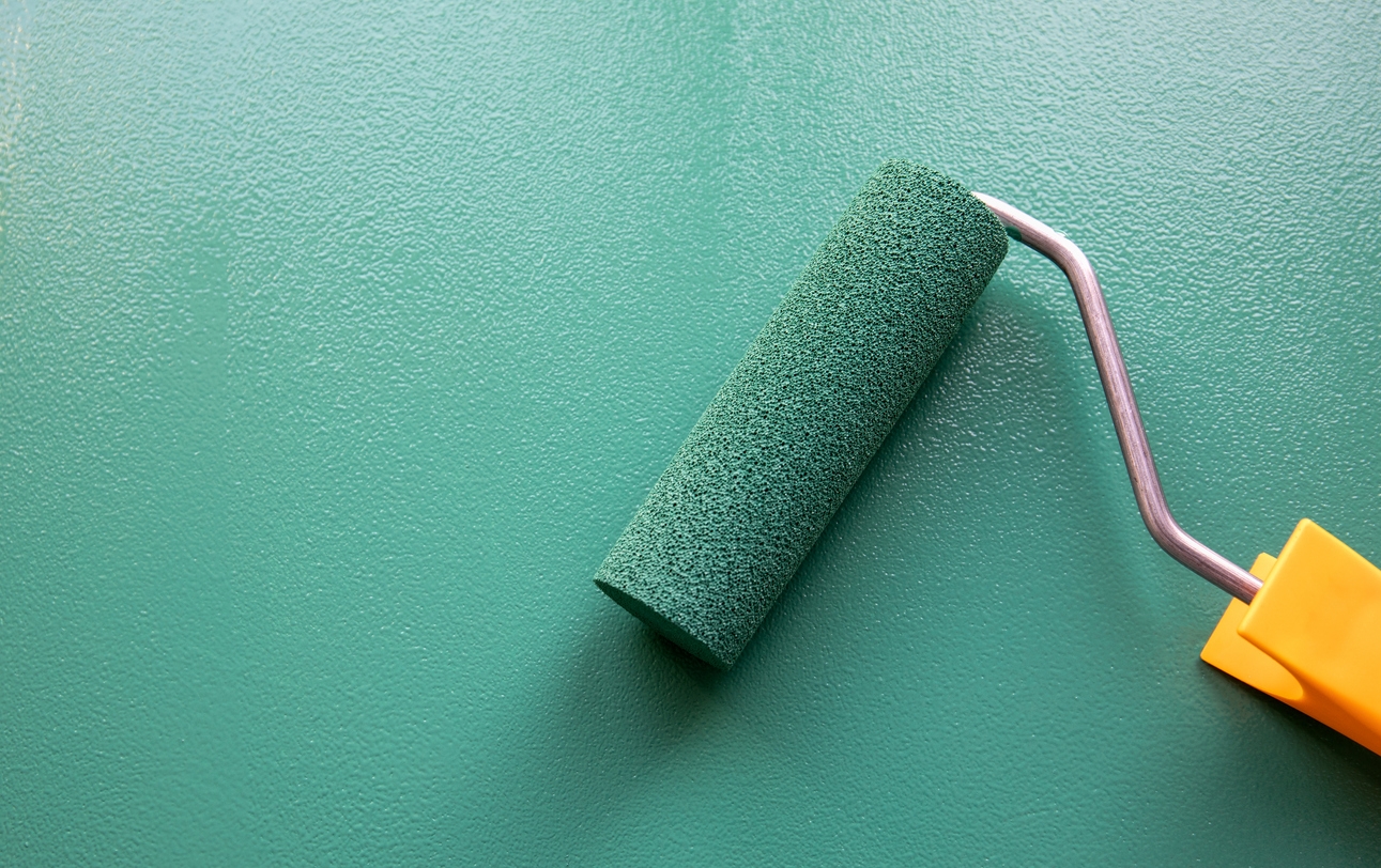 Paint roller with green color on painted wooden surface with a chalk board finish being painted on a Dublin, CA commercial building